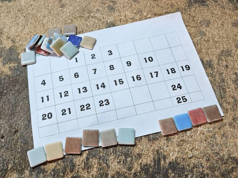 Kalendář a keramické mozaikové dlaždice uspořádané na pracovním stole